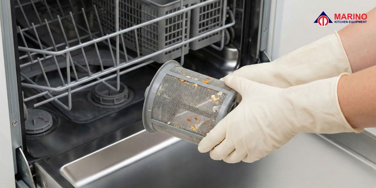 A sleek stainless steel built-in dishwasher machine installed in a luxury modern kitchen with wine glasses on the counter.